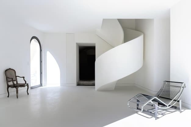 Interior of a 3D-printed home, showing a minimalist living space with smooth, curved walls made of concrete. The room is furnished with modern, eco-friendly furniture, and natural light streams through a large window, creating a bright and inviting atmosphere.