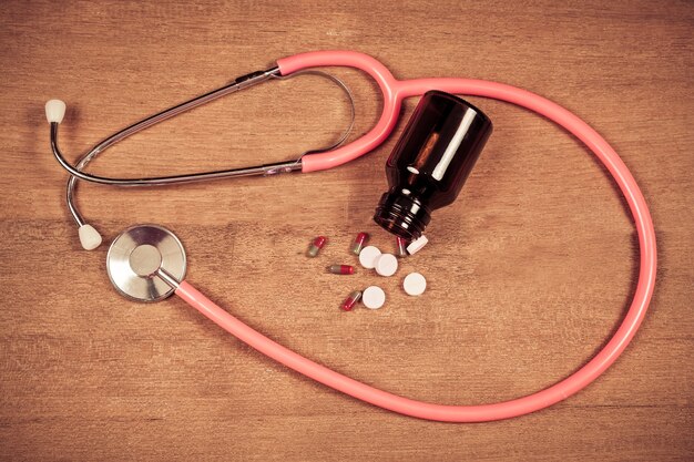 A close-up shot of prescription medication bottles with a stethoscope draped over them. Focus on the high cost of prescription drugs.